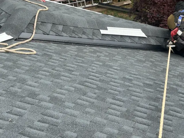 Roofer installing ridge vent on a new architectural shingle roof