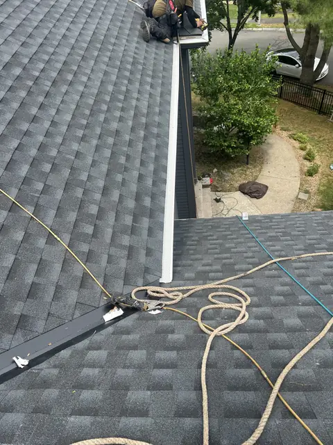 Nearly finished shingle roof with a metal valley and a new gutter guard at the eave